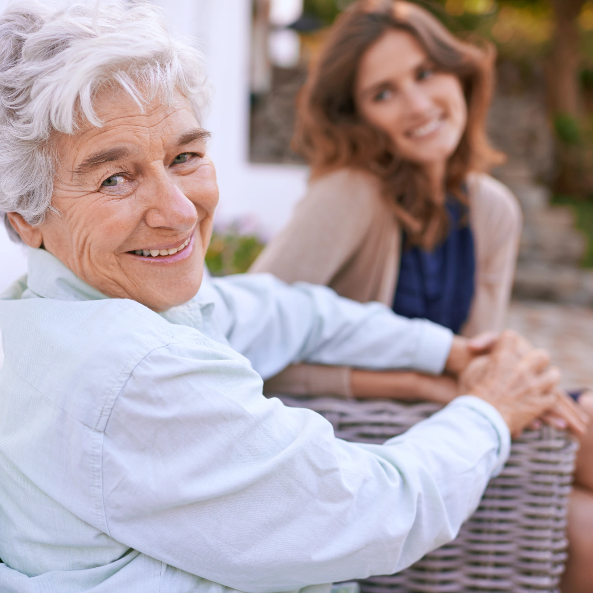 senior woman and happy caregiver smiling at the camera